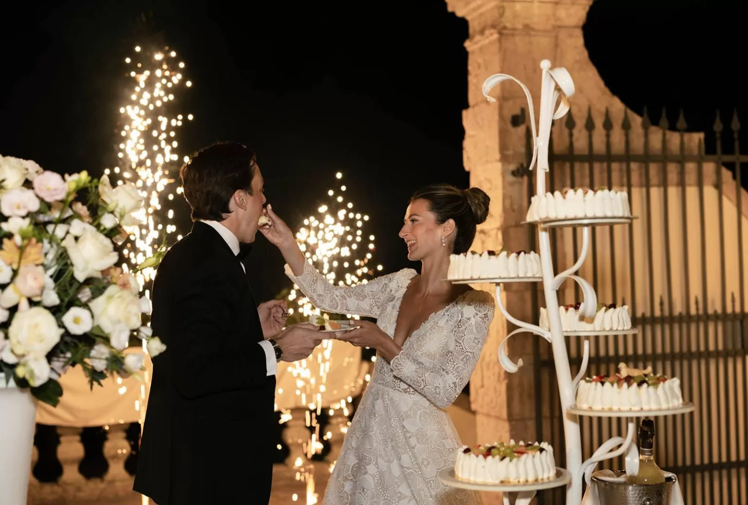 Bride and groom cutting a floral wedding cake under string lights at Villa Cariola.