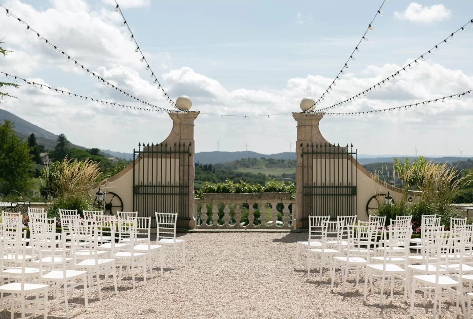 Elegant outdoor ceremony setup at Villa Cariolla with white chairs and string lights against rolling hills.