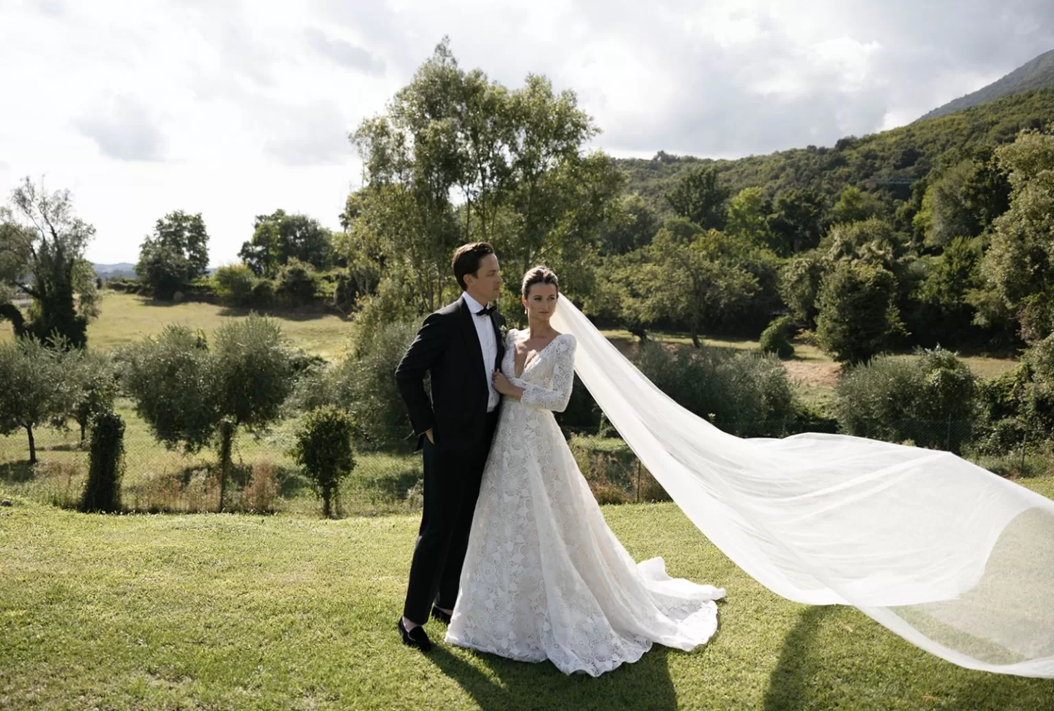 Bride’s lace gown and flowing veil captured in the breeze on the lush lawn of Villa Cariolla.