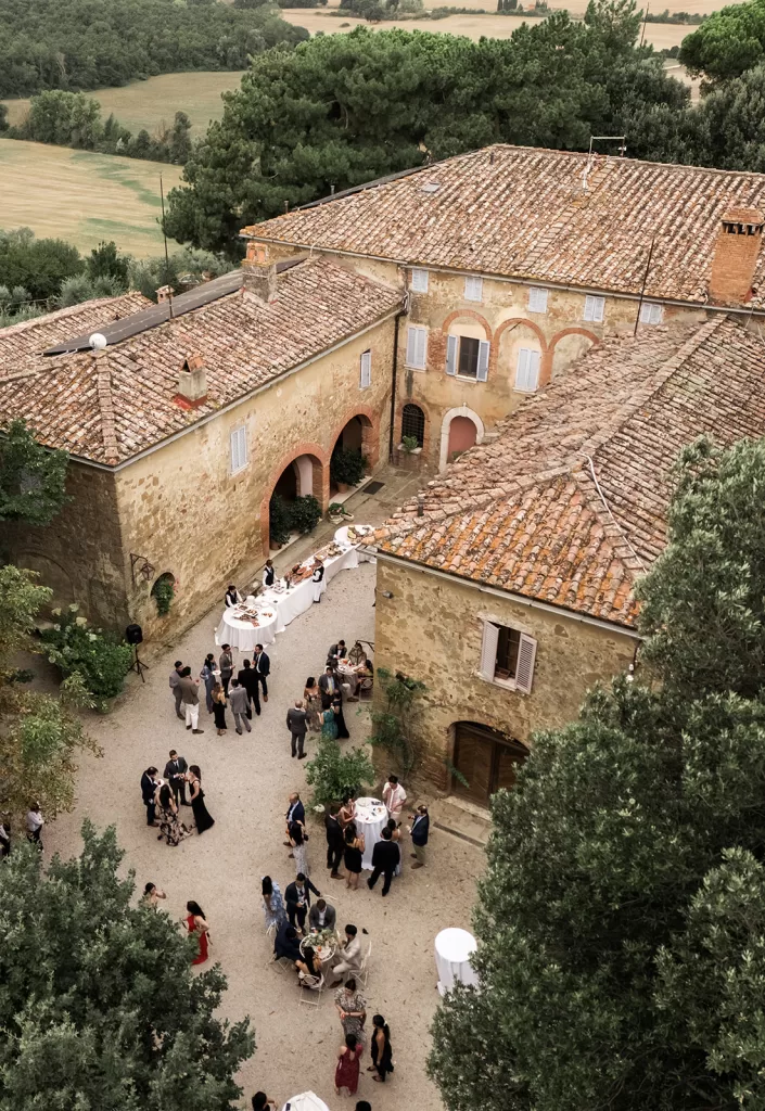 Guests gather in the rustic courtyard of Borgo Sant’Ambrogio for a relaxed wedding aperitivo beneath the terracotta rooftops.