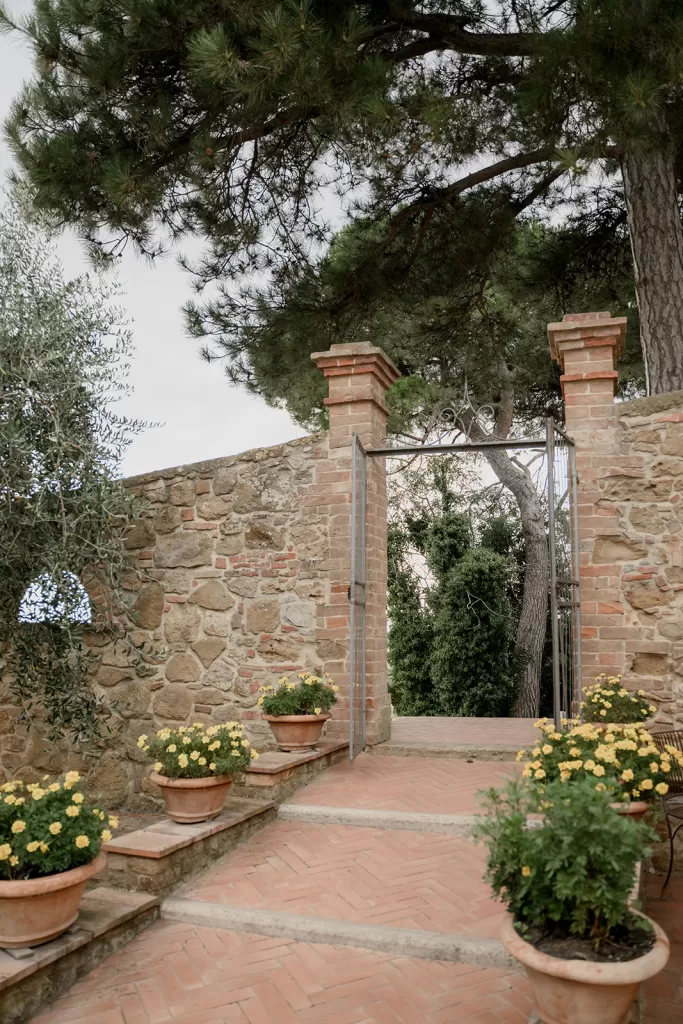 Charming stone entryway framed by yellow flowers and iron gate at Borgo Sant'Ambrogio.