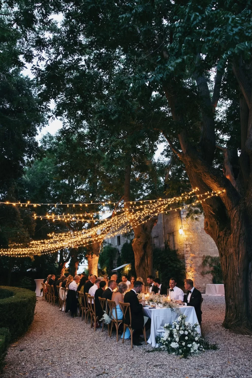 Romantic evening reception at Borgo Stomenanno with fairy lights strung above long banquet tables.