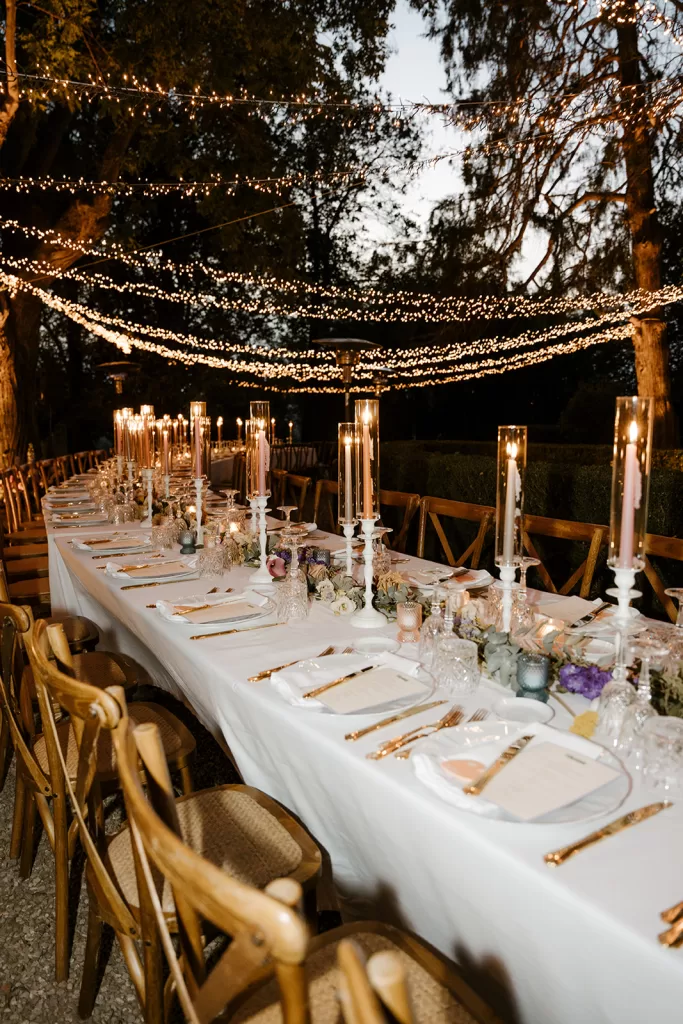 Elegant wedding reception setup at Borgo Stomennano with taper candles and romantic lighting beneath the trees.