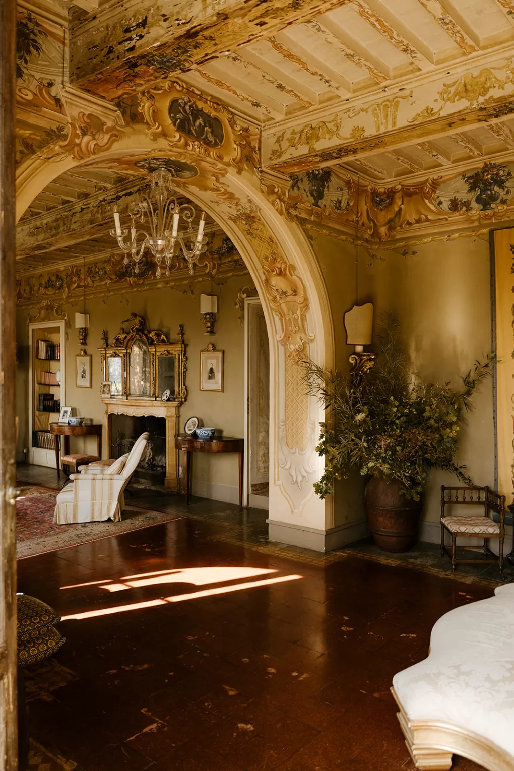Elegant interior at Borgo Stomennano featuring frescoed arches, antique furniture, and golden lighting.