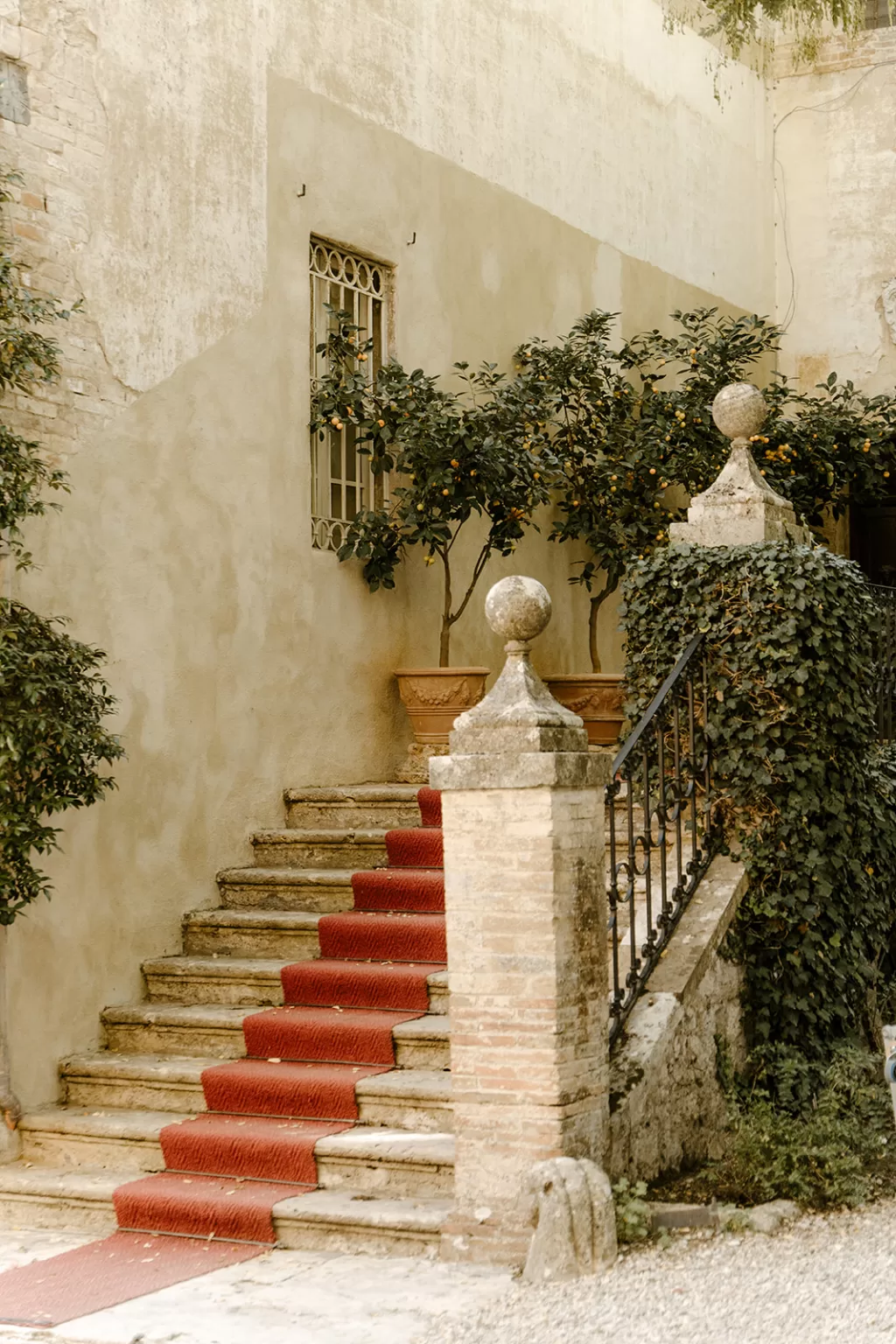 Timeworn stone staircase with red carpet runner and lemon trees outside Borgo Stomennano.