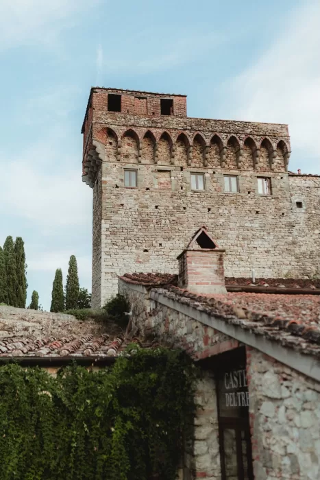 Close-up of the medieval stone tower of Castello del Trebbio against a blue sky.