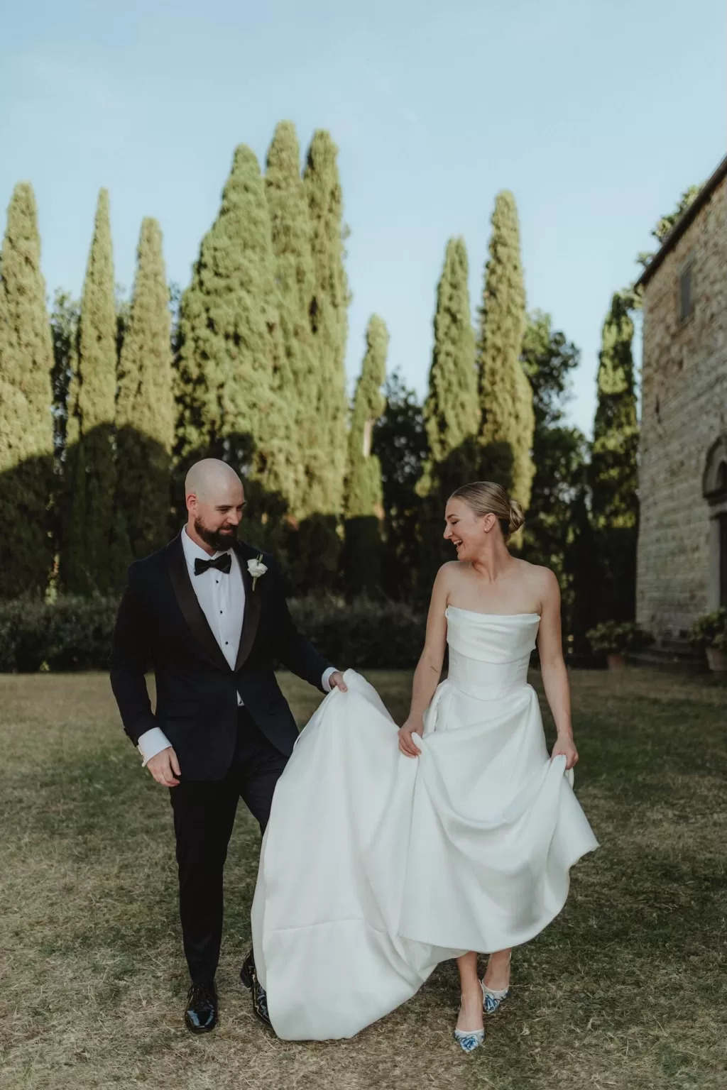 Bride and groom smiling while walking together on the lawn at Castello del Trebbio.