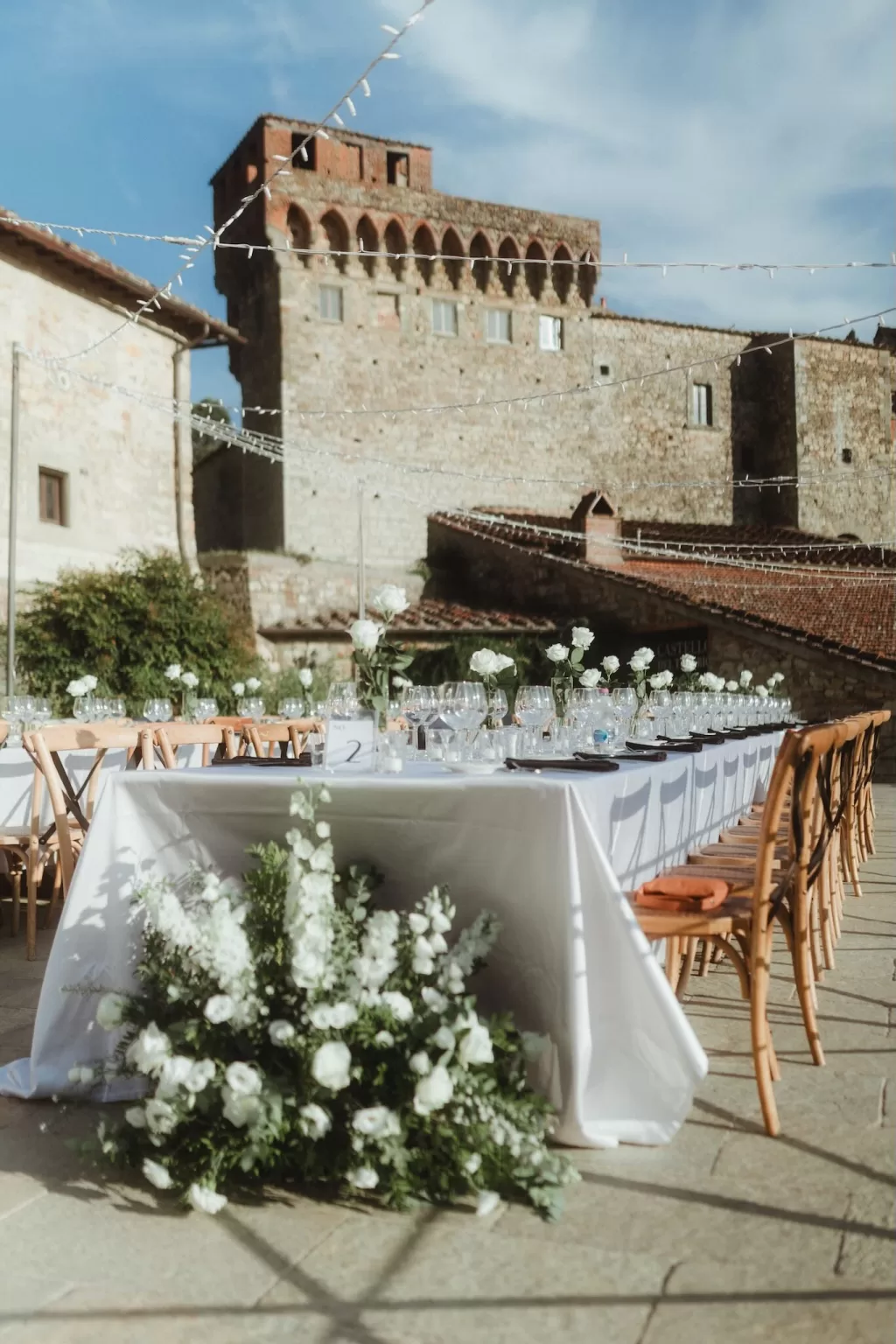 Elegant wedding reception table with white flowers set in front of Castello del Trebbio.