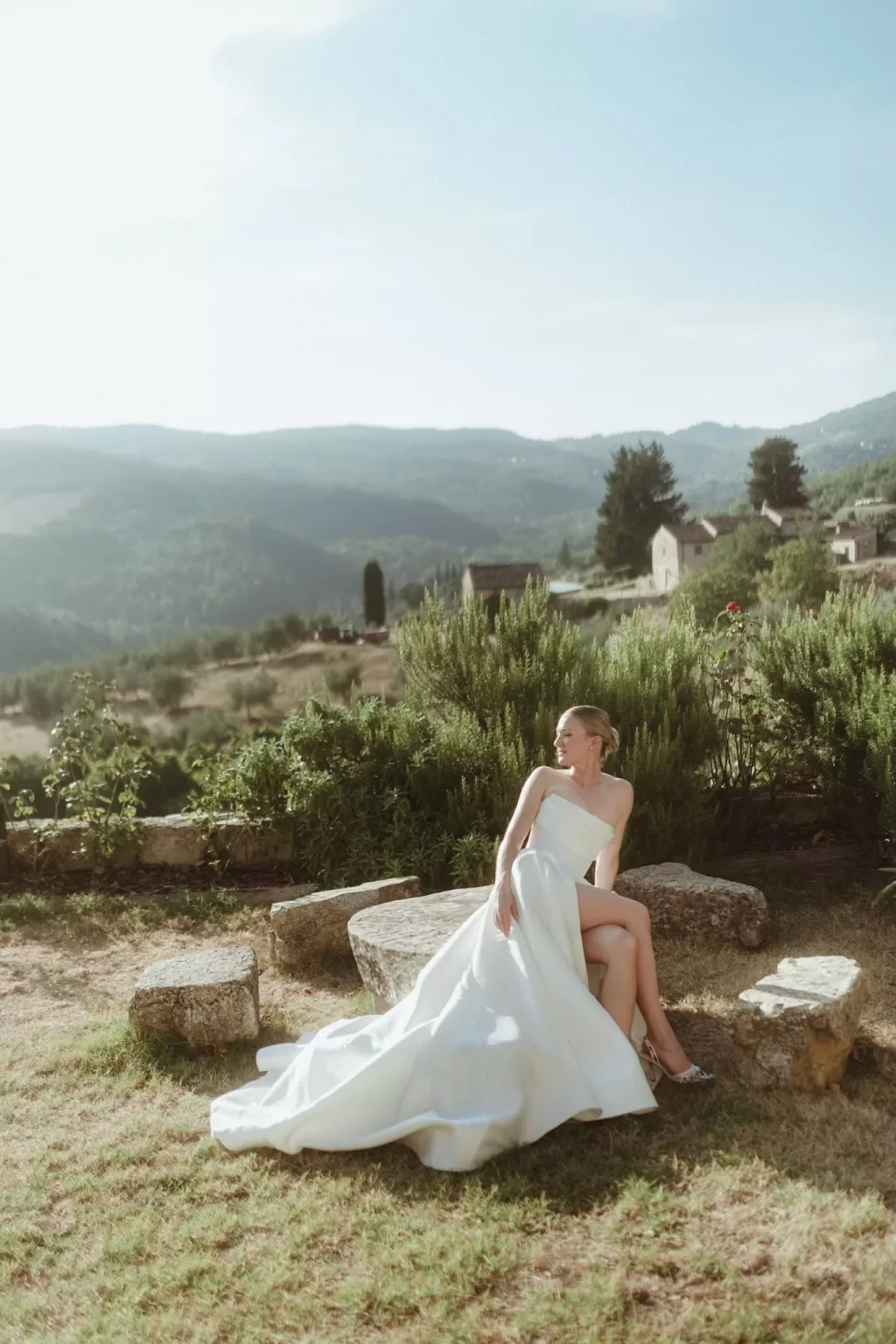 Bride seated gracefully on stone benches overlooking the Tuscan countryside at Castello del Trebbio.