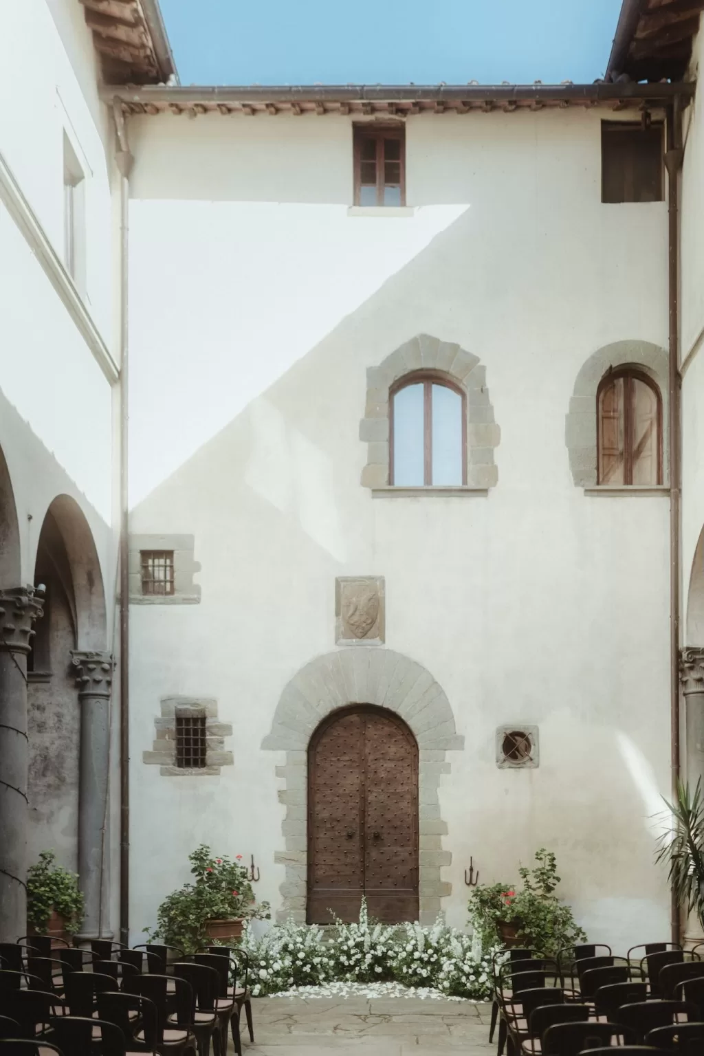 Courtyard ceremony setup with rows of chairs and floral aisle decor at Castello del Trebbio.