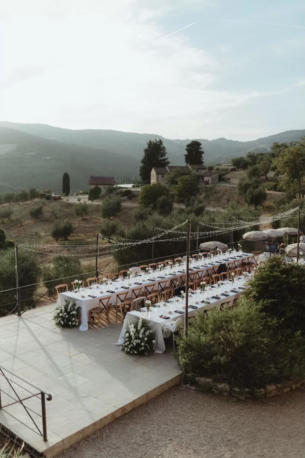 Panoramic view of long reception tables set on the terrace with Tuscan countryside backdrop at Castello del Trebbio.