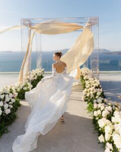 Editorial bridal portrait at Cavo Ventus, with a dramatic veil caught in the wind against the island’s volcanic backdrop. Shot by The Duo Photography.