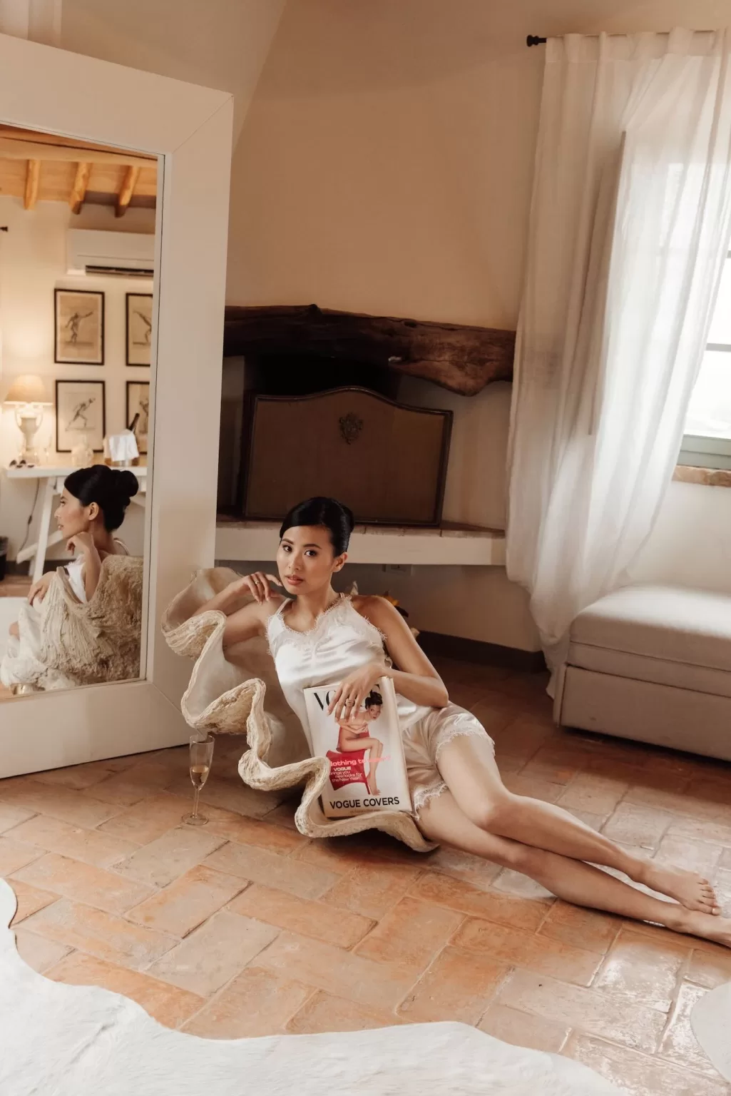 Bride in silk loungewear posing with a Vogue magazine in a serene suite at Conti di San Bonifacio.