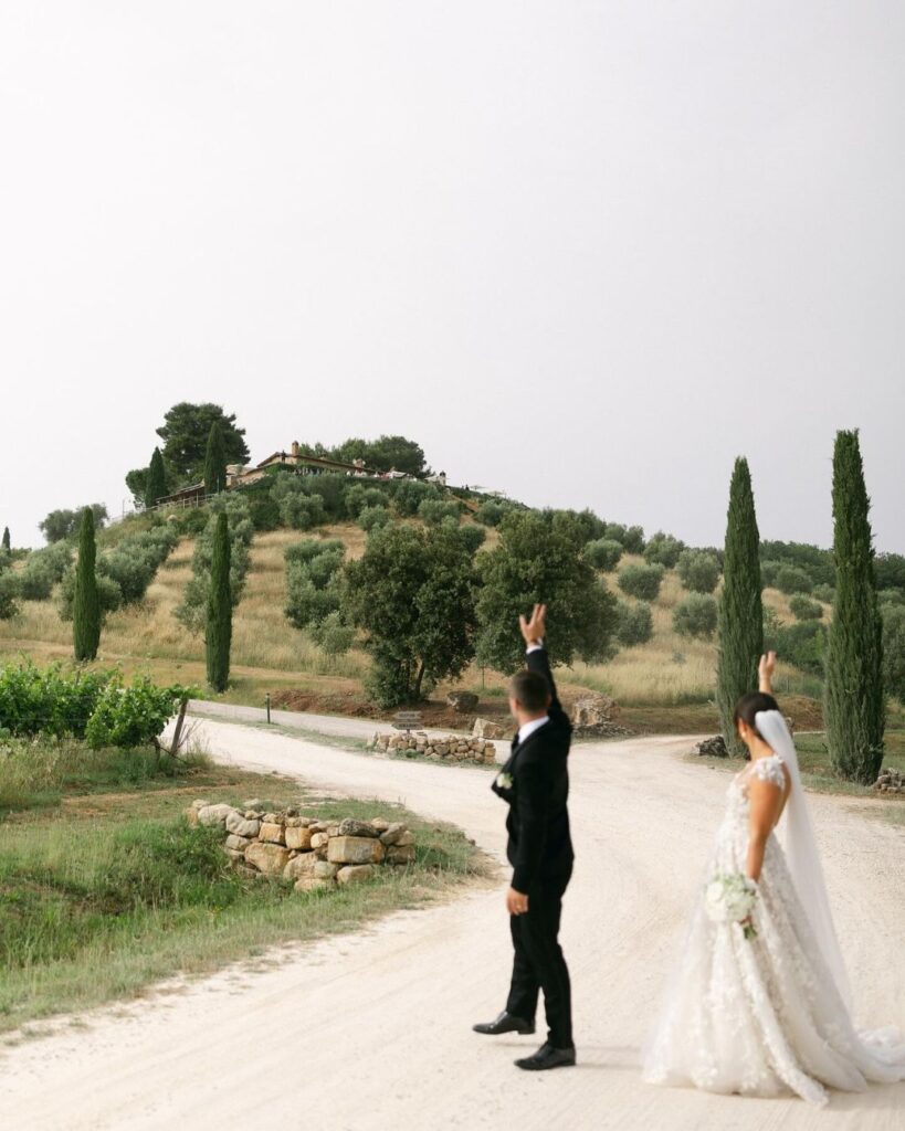 Newlywed couple embracing with the rolling Tuscan hills in the background at Conti di San Bonifacio, captured by Alex Wysocki.