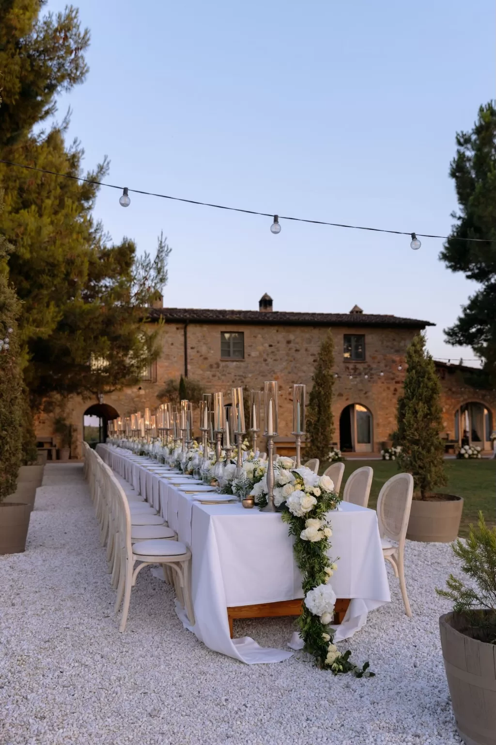 Long candlelit reception table set in the courtyard of Conti di San Bonifacio, ready for dinner under string lights.
