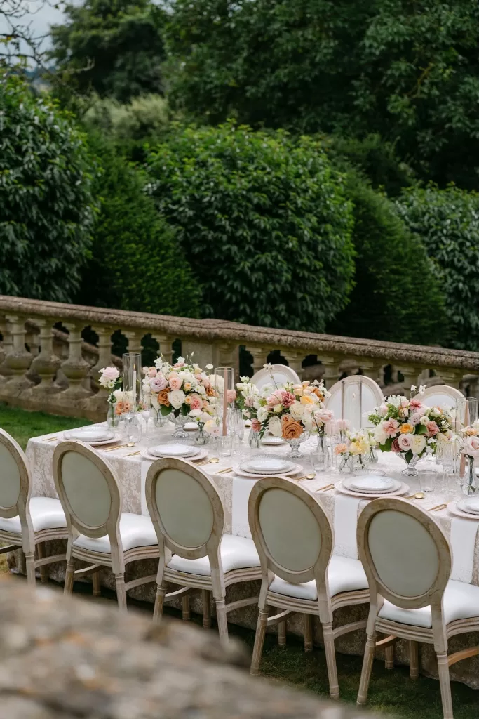 Elegant outdoor wedding reception setup at Euridge Manor with a long table adorned with blush and peach floral arrangements.