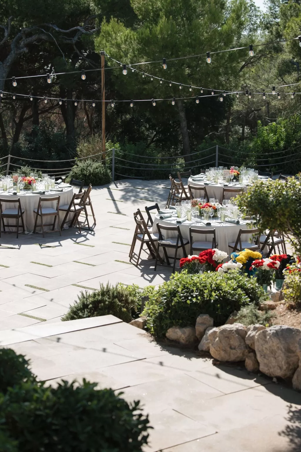 Garden reception setup at Masia Casa del Mar with round tables, string lights, and colorful flowers ready for a romantic evening celebration.