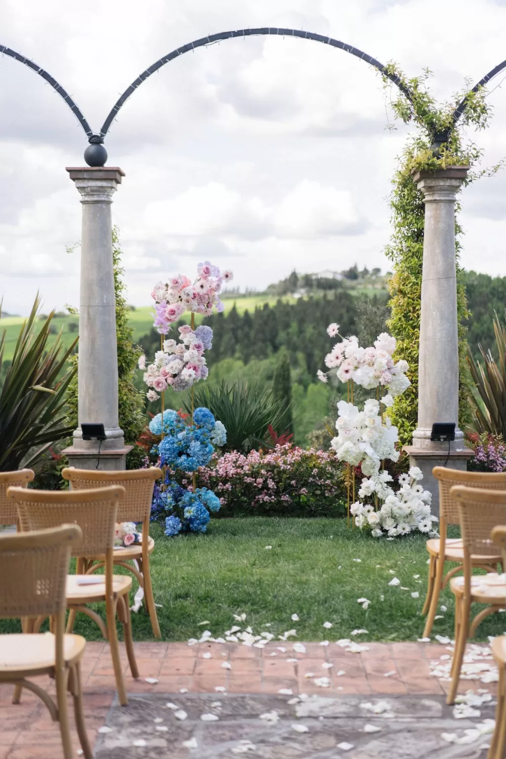 Scenic aisle view at Tenuta Corbinaia after the ceremony with scattered white petals and countryside in the distance.