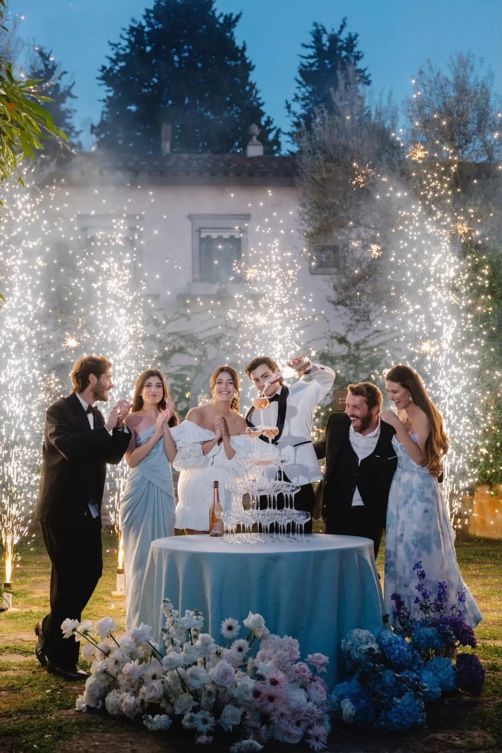 Newlyweds and friends celebrating with a champagne tower and sparklers lighting up the night at Tenuta Corbinaia.