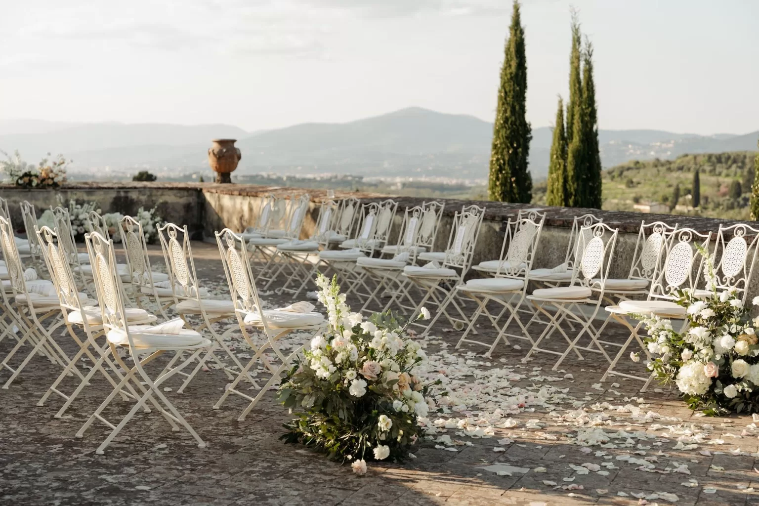 Ceremony chairs and scattered petals on the terrace after a wedding at Villa di Maiano.