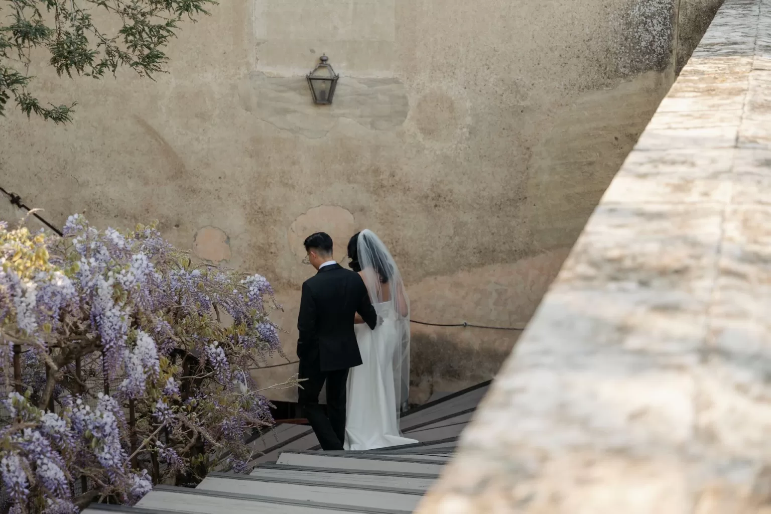 Bride and groom walking hand in hand on the stone terrace of Villa di Maiano