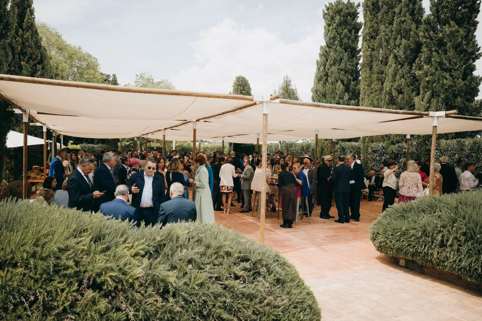 Guests mingling under shaded canopy during outdoor cocktail reception at Masia Aldamar.