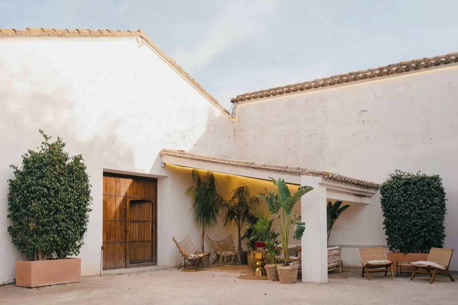 Cosy courtyard lounge with wooden doors and tropical plants at Masia Aldamar