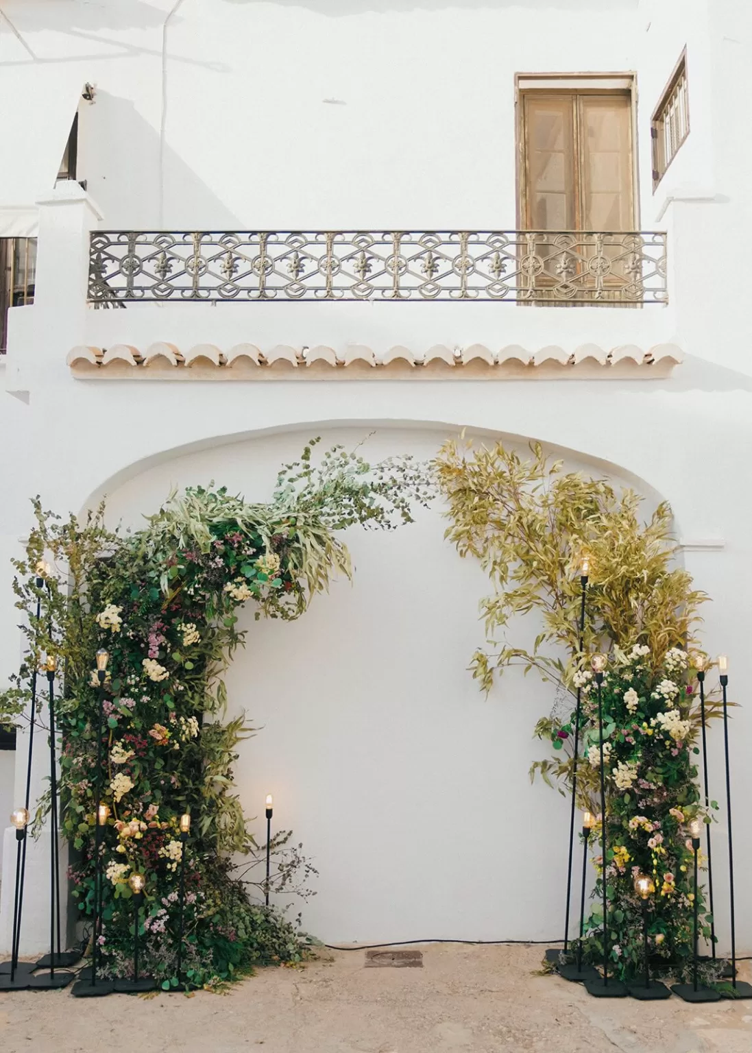 Romantic floral arch installation against white Spanish wall at Masia Aldamar wedding ceremony