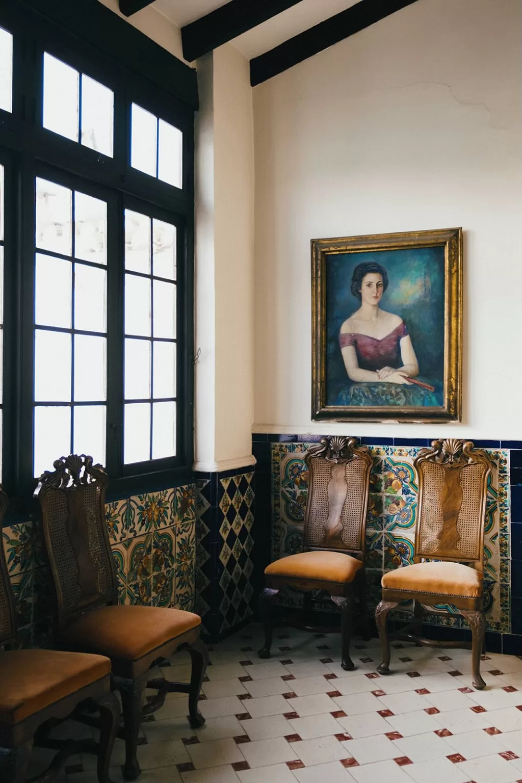 Historic tiled room at Masia Aldamar with antique chairs and framed portrait