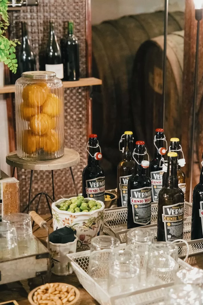 Vermouth bottles, green olives, and glasses set up for an aperitivo at Masia Aldamar