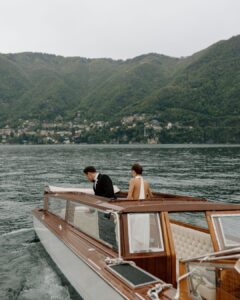 A newlywed couple stands on the deck of a yacht, the ocean stretching behind them, captured by Arlene Leilani.