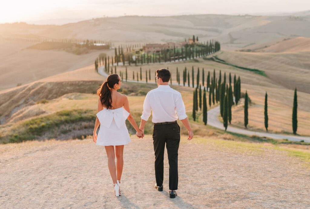 Newlyweds embracing on a mountain, with a vast landscape behind them