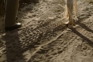 The couple leaves a trail of footprints in the sand as they walk along the shoreline, lost in the moment.