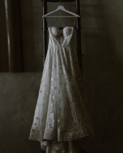A wedding dress elegantly hung up near a window at Areias do Seixo, softly illuminated by natural light before the ceremony.