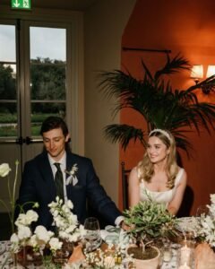 The newlyweds share a private moment at their reception table, surrounded by candlelight and elegant floral decor.