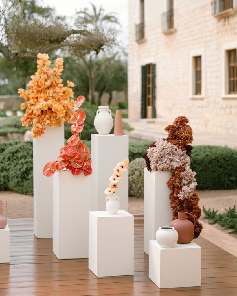 Artistic wedding altar decor with vibrant floral sculptures in shades of coral and cream at Finca Morneta.