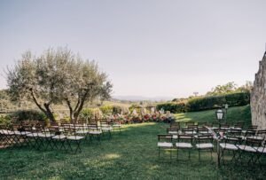 A beautiful outdoor ceremony setup at Quercia al Poggio, with wooden chairs neatly arranged under the Tuscan sky.