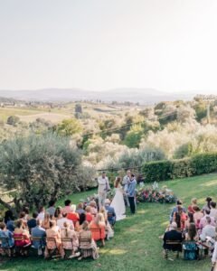 A breathtaking wide-angle view of the ceremony setup at Quercia al Poggio, framed by vineyards and olive trees.