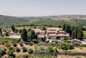 The grand entrance of Quercia al Poggio, framed by historic stone walls and lush greenery.