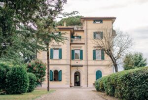 Villa Donna Camilla from above at sunset, bathed in golden light with the rolling countryside in the background.