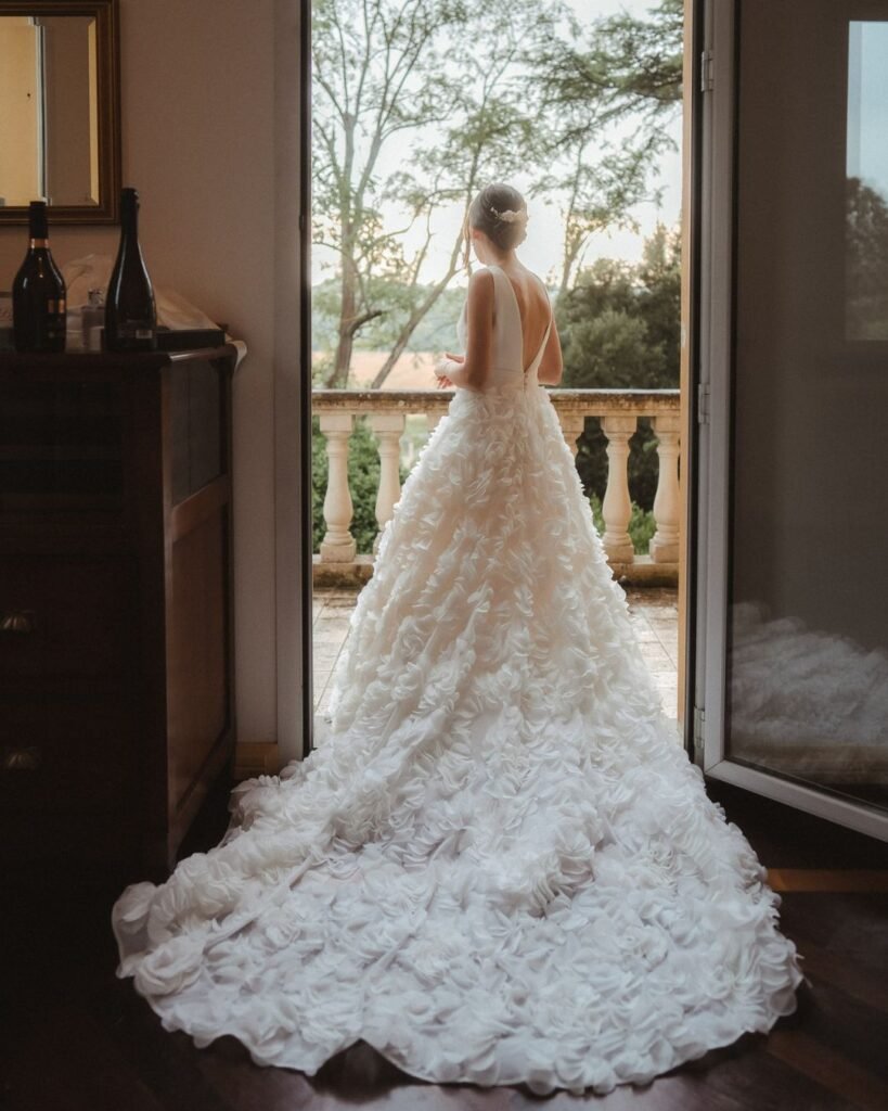 The bride gazes out of a grand window at Villa Donna Camilla, bathed in soft morning light.