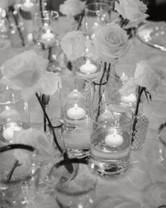 Soft candlelight reflects off glass vases filled with delicate white flowers at Villa Donna Camilla’s reception tables.