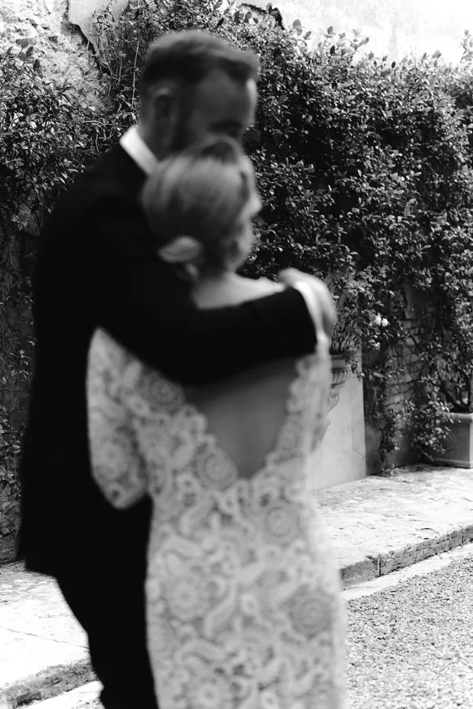 Soft black-and-white photo of a romantic embrace in the ivy-covered courtyard at Borgo Stomennano