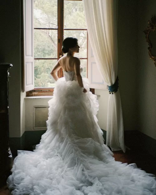 The bride stands by the window, bathed in soft natural light, moments before the ceremony.
