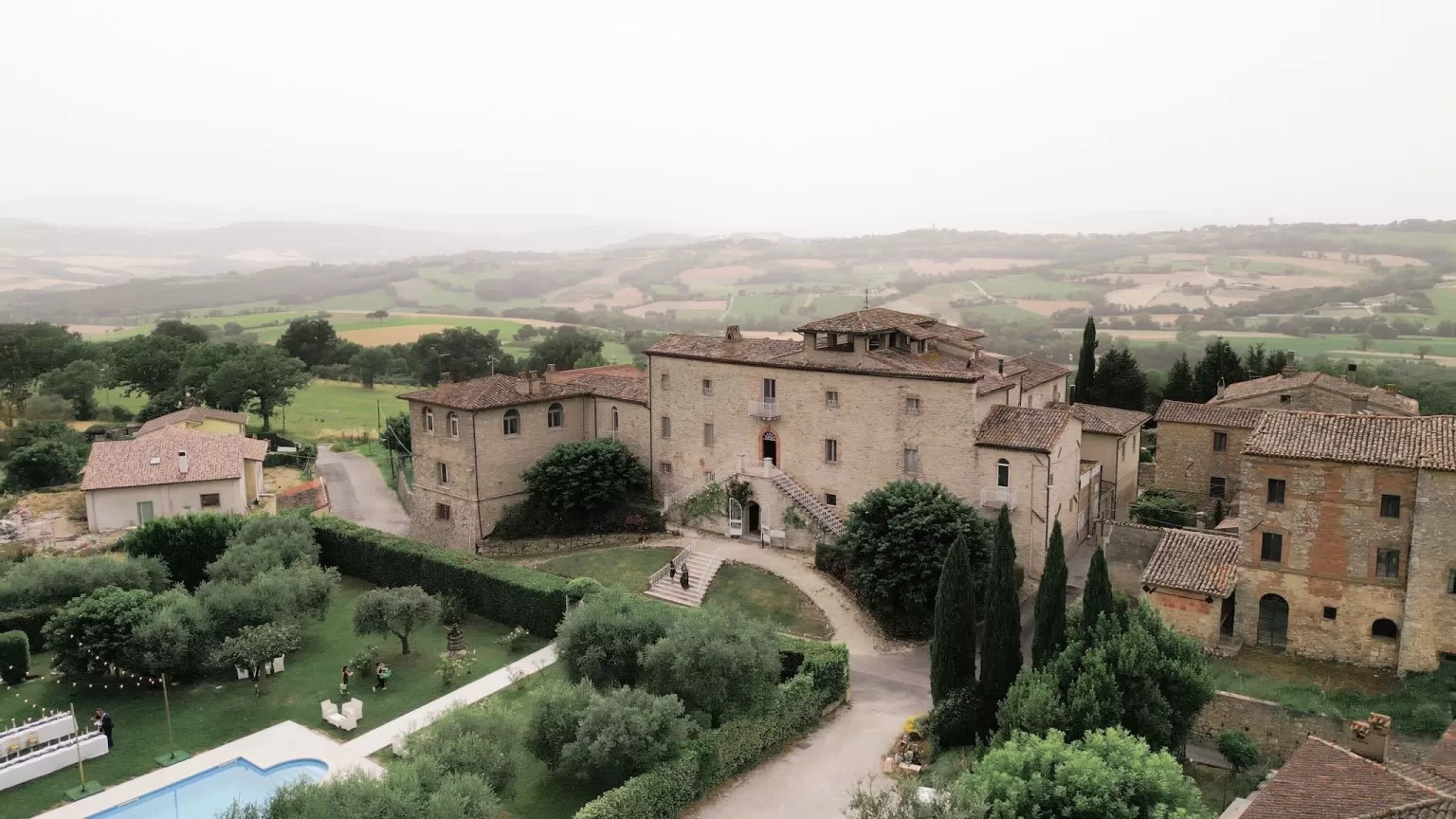 Aerial view of Castello di Montignano and surrounding Umbrian countryside with olive trees and stone villas.