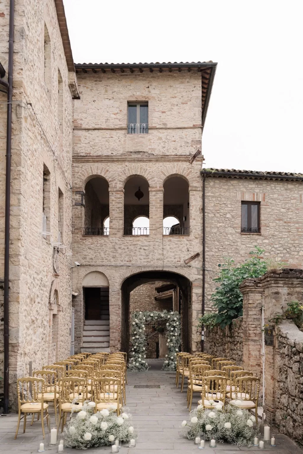 Elegant ceremony setup framed by stone archways and floral arch at Castello di Montignano.