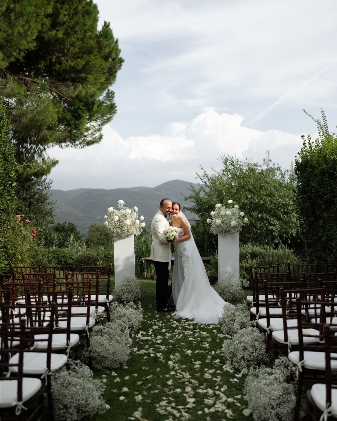 The newlyweds share a moment at the altar, surrounded by flowers and mountain views at Castello Montignano.