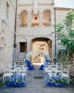 Romantic courtyard ceremony setup at Castello Montignano with vibrant blue and white flower installations.