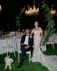 Bride and groom pose with their dog under glowing chandeliers at Castello Montignano, surrounded by lush florals and soft candlelight.