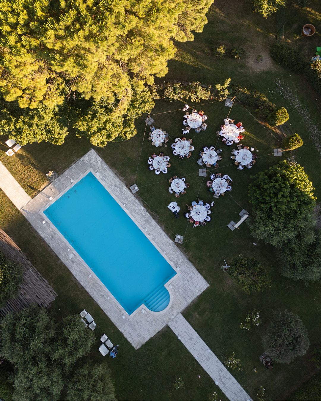 Aerial view of wedding dinner setup beside the turquoise pool at Castello Montignano
